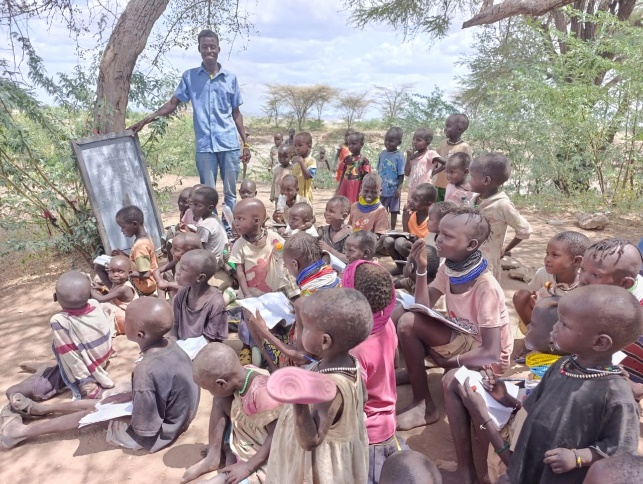 Volunteer teacher with village children in Kakuma